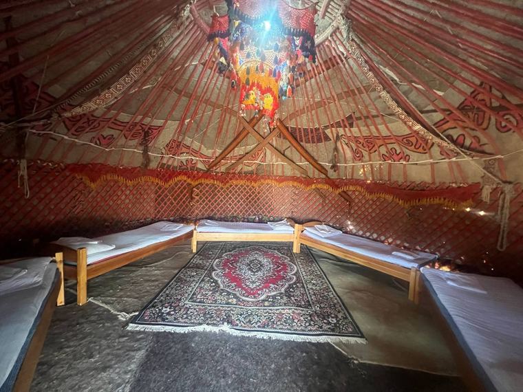 Inside a yurt at Sputnik Navoi with low beds and a patterned carpet
